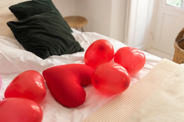 Rote Ballone und Herz formten Kissen auf Bett
