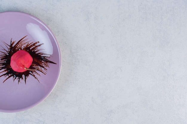 Rote Birne mit Schokolade in der violetten Platte auf grauem Hintergrund.