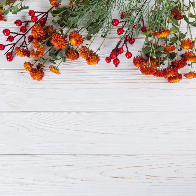 Rote Blumen mit den Beeren zerstreut auf Holztisch