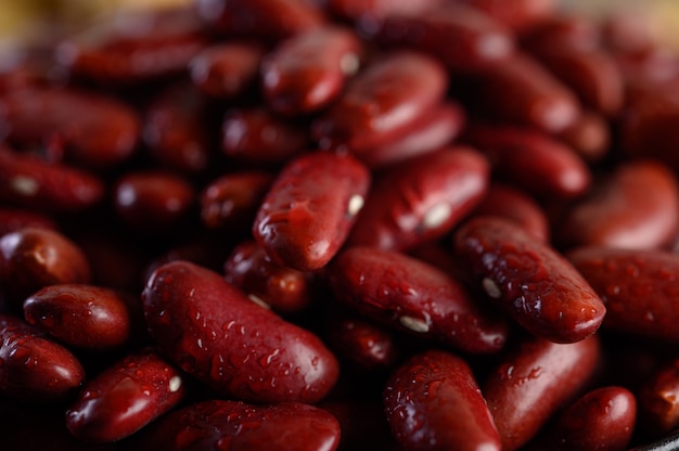 Rote Bohnen in einer hölzernen Schüssel und mit Wassersprayon der schwarze Zementboden.