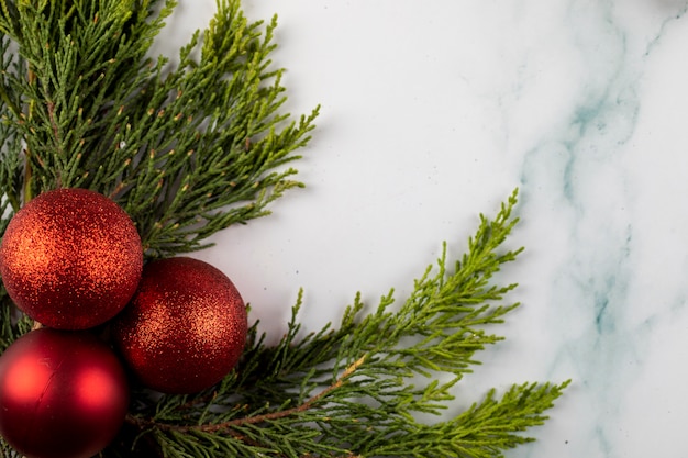 Rote Christbaumkugeln auf einem grünen Zweig in der Ecke.