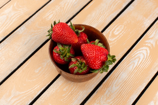 Kostenloses Foto rote erdbeeren der draufsicht innerhalb des braunen topfes auf dem hölzernen schreibtisch