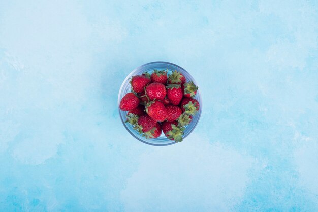 Rote Erdbeeren in einer Glasschale auf Blau