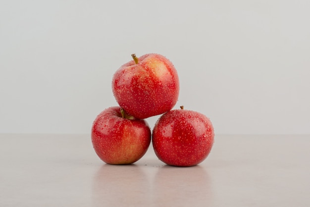 Rote, frische Äpfel auf weißem Tisch.
