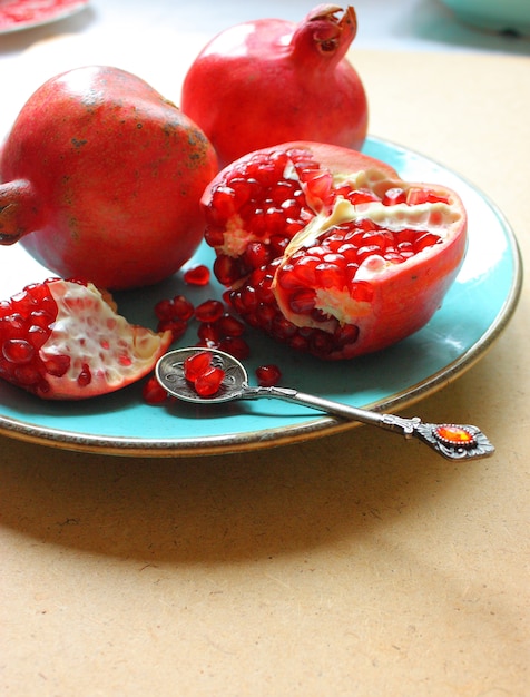 Rote ganze und geschnittene Granatäpfel in der Platte