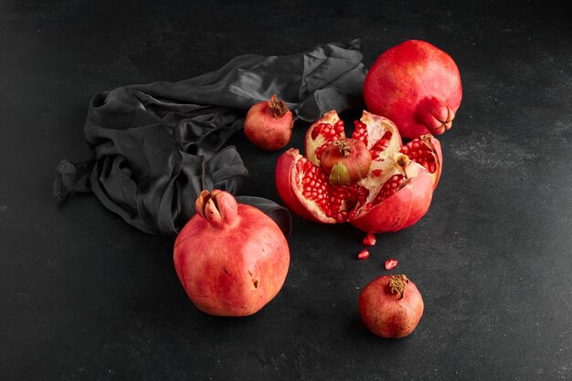 Rote Granatäpfel auf schwarzer Tischdecke und Raum, Winkelansicht.