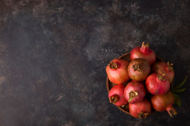 Rote Granatäpfel in einer Holzplatte auf Marmor