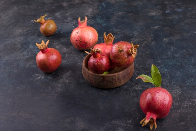 Rote Granatäpfel in einer Holzplatte und auf dem Marmortisch