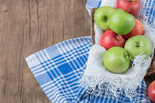 Rote, grüne Äpfel auf einem weißen Handtuch in einem Korb