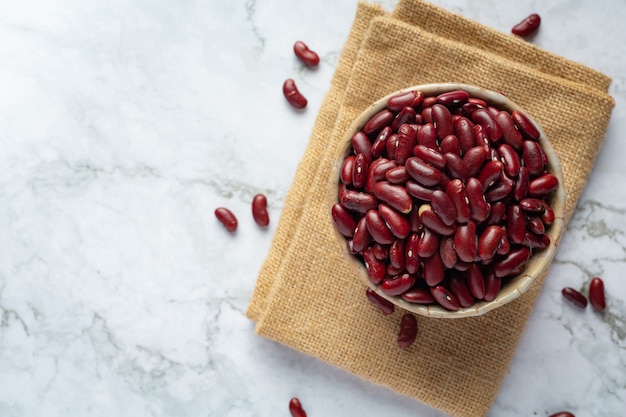 Rote Kidneybohnen in einer kleinen Schüssel auf Sackstoff legen