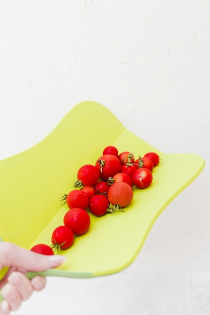 Rote Kirschtomaten auf Schneidebrett gegen weißen Hintergrund