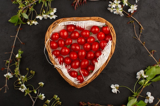 rote Kirschtomaten der Draufsicht frisch im Korb auf dem dunklen Hintergrund