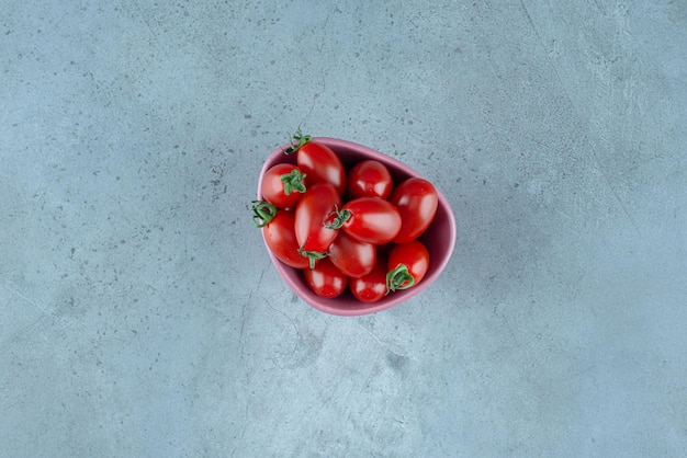 Rote Kirschtomaten in einer Tasse auf Blau.