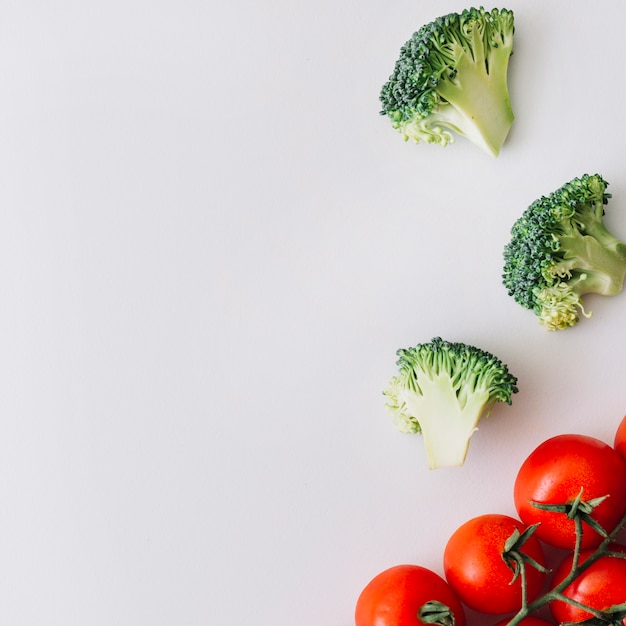 Rote Kirschtomaten und frische Broccolisscheiben gegen weißen Hintergrund