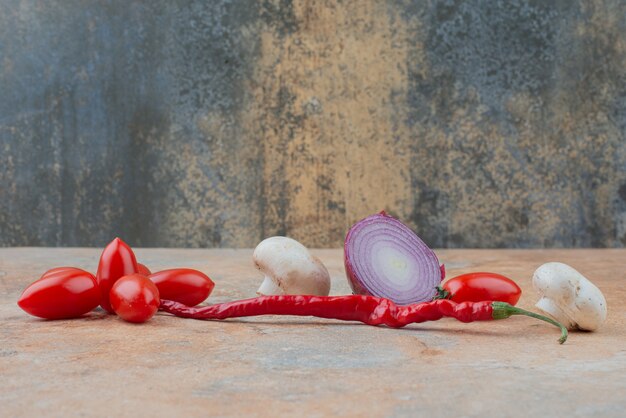 Rote Kirschtomaten, Zwiebeln und Chili auf Marmor.