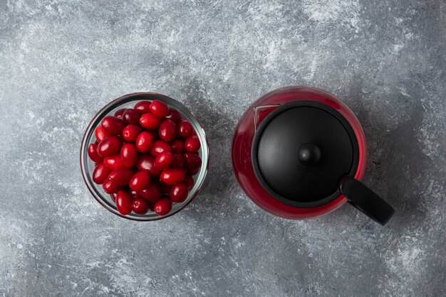 Rote Kornelkirschen in einer Glasschale mit Saft im Kessel.