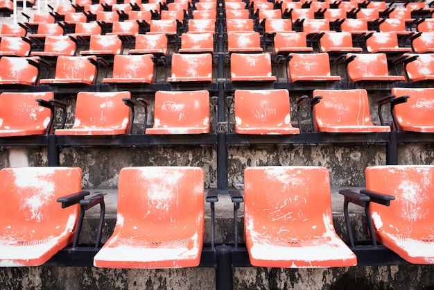 Rote leere und alte Plastiksitze im Stadion.