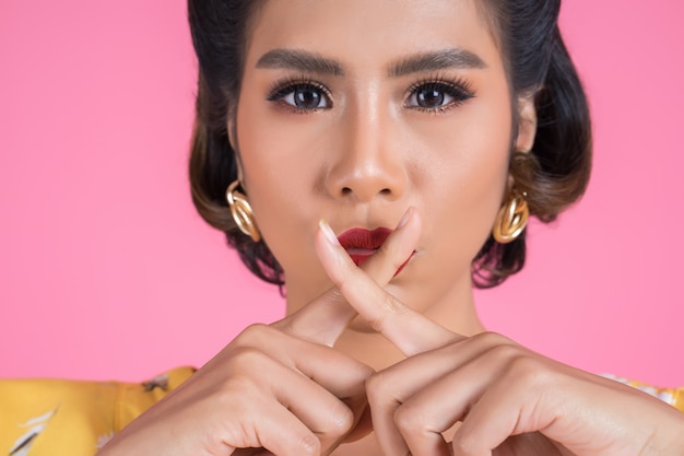 Rote Lippen und Finger der asiatischen Frau der Schönheit, die Stillezeichen zeigt