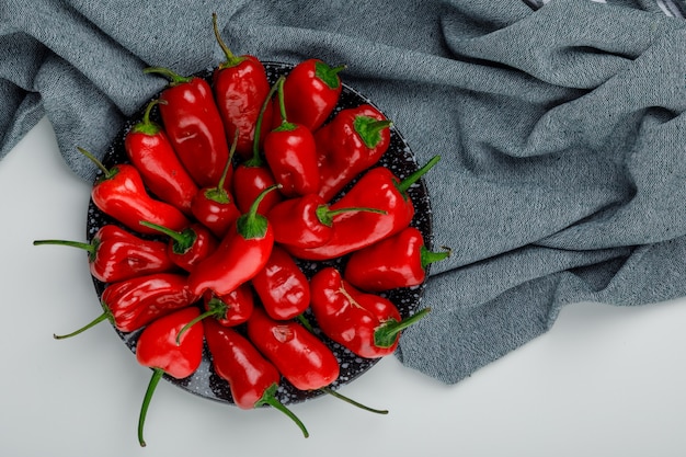 Kostenloses Foto rote paprika in einer flachen platte lagen auf einer weißen und textilen wand