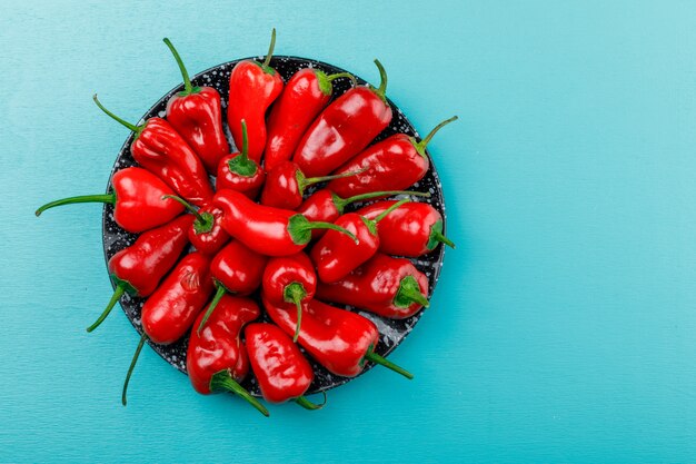 Rote Paprika in einer Keramikschale auf blauer Wand, flach liegen.