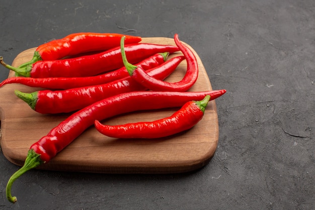 Rote Peperoni von oben aus der Nähe auf einem horizontalen Schneidebrett auf dem schwarzen Tisch mit Kopierraum