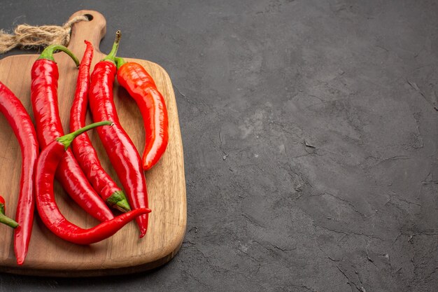 Rote Peperoni von oben aus der Nähe auf einem Schneidebrett auf der linken Seite des schwarzen Tisches mit Kopierraum