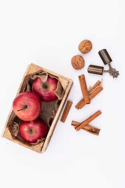 Rote Äpfel in der Holzkiste auf weißer Oberfläche