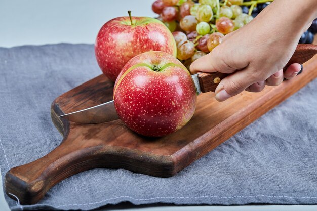 Rote Äpfel und Weintrauben auf einem Holzbrett.