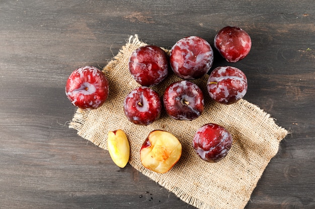 Rote Pflaumen mit Stück Sack Draufsicht auf einer grungy Oberfläche