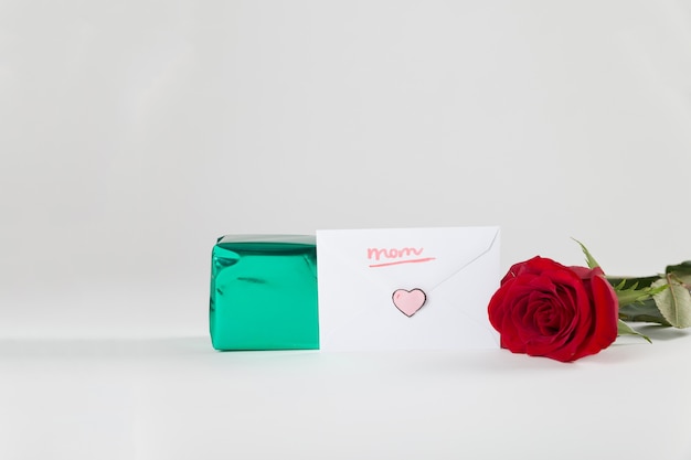 Rote Rose neben Geschenkbox und Umschlag