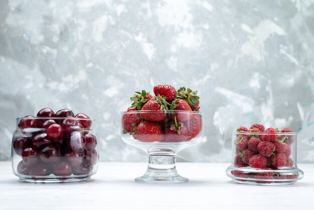 rote Sauerkirschen frisch ganz und weich mit Erdbeeren und Himbeeren auf hellem Schreibtisch