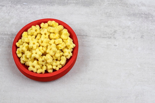 Rote Schüssel voll köstlicher Cornflakes auf Steintisch.