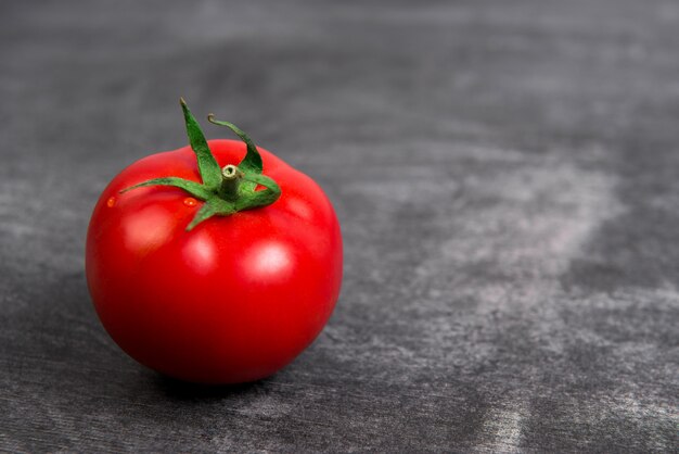 Rote Tomate auf grauem Holztisch