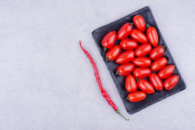 Rote Tomaten in einer schwarzen Platte mit Chili-Pfeffer