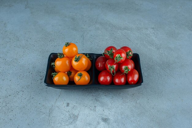 Rote und gelbe Kirschtomaten in einer schwarzen Servierplatte.