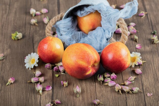 Rote und gelbe Pfirsiche auf blauem metallischem Eimer auf Tuch.