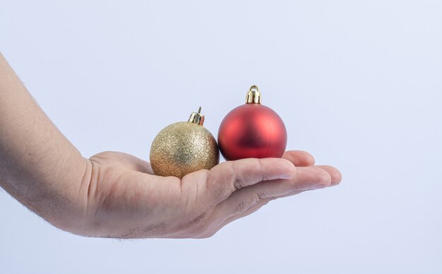 Rote und goldene glitzernde Kugeln in der Hand halten