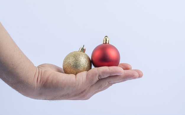 Rote und goldene glitzernde Kugeln in der Hand halten