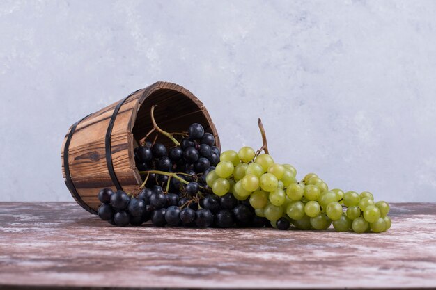 Rote und grüne Weintrauben aus einem Holzeimer.
