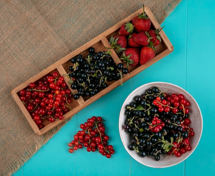 Kostenlose Foto rote und schwarze johannisbeeren der draufsicht mit erdbeeren auf einem blauen hintergrund