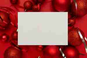 Kostenloses Foto rote weihnachtskugeln und leere karte auf rotem tisch
