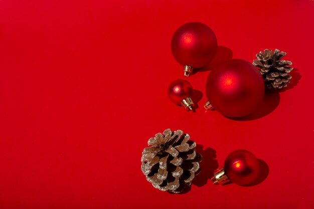 Rote Weihnachtskugeln und Tannenzapfen auf rotem Tisch