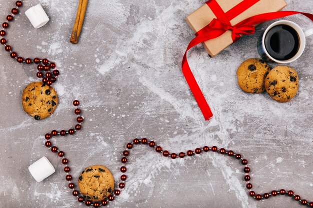 Rote weiße Süßigkeiten, Plätzchen, Eibisch, Tasse Kaffee und Präsentkarton liegen auf grauem Boden