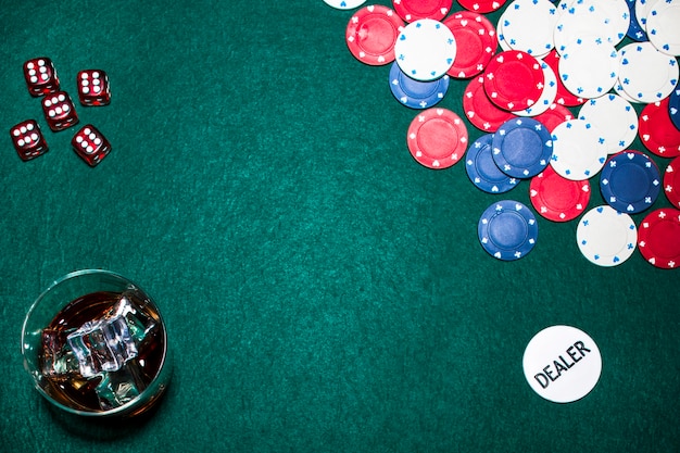 Rote Würfel; Whiskyglas; Casino-Chips; und Händlerchip am Pokertisch