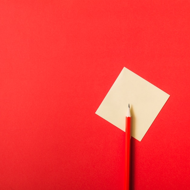 Roter Bleistift auf gelbem leerem Papier über rotem Hintergrund