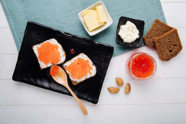 Roter Kaviar-Toast-Roggenbrot der Draufsicht mit Hüttenkäsebutter-Holzlöffel und Mandel