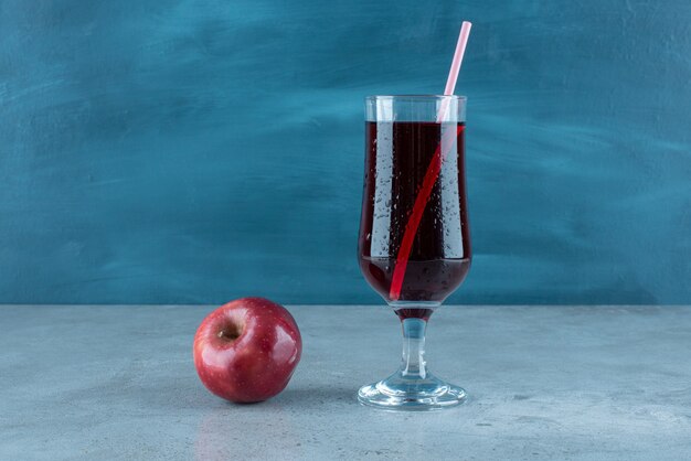 Roter leckerer Saft mit frischem Apfel und Stroh.