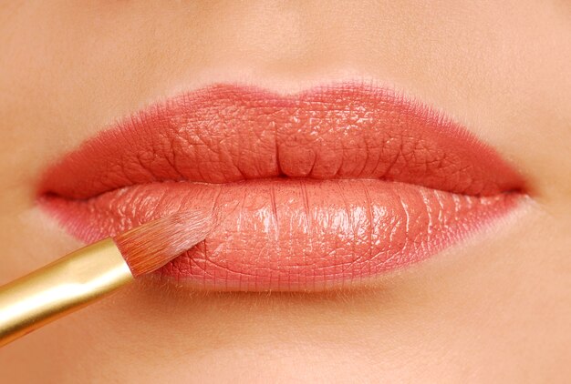 Roter Lippenstift-Kosmetikpinsel. Make-up-Tool. Frauenlippen schließen sich.