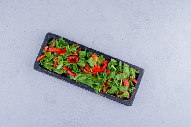 Roter Paprika- und Kopfsalatsalat in einem kleinen Behälter auf Marmorhintergrund. Foto in hoher Qualität