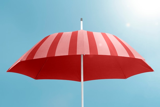 Roter Regenschirm mit Kopienraum auf Hintergrund des blauen Himmels